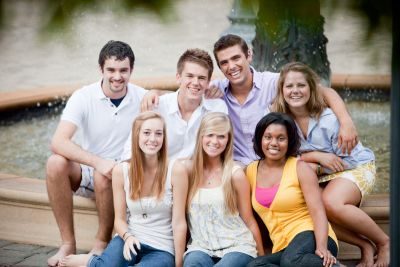 A group of students sitting beside a fountain.