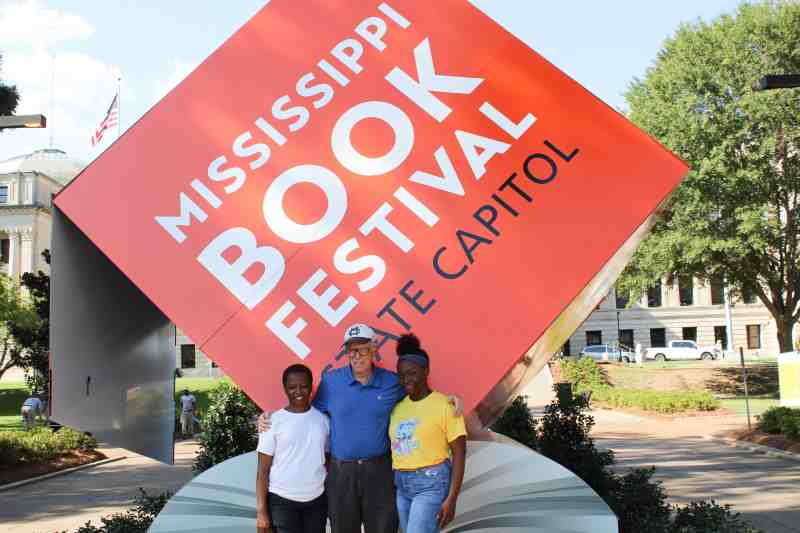 Mississippi College grads Andrea Jones-Davis and her sister, Brittany N. Jones flank MC university news coordinator Andy Kanengiser at the 2019 Mississippi Book Festival in Jackson. Both MC School of Education graduates,the sisters serve as instructional leaders at the Toot, Teach and Roll Mobile Learning Lab in Jackson at the Aug. 17 event.  The lab is housed in a big bus that was parked near the Capitol, with activities attracting kids. 