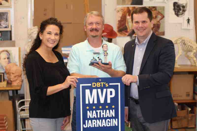 Dr. Blake Thompson, right, Mississippi College president, and Lori Bobo, university events coordinator and March DBT’s MVP, present Nathan Jarnagin with the honorary bobblehead signifying his selection as the April DBT's MVP.