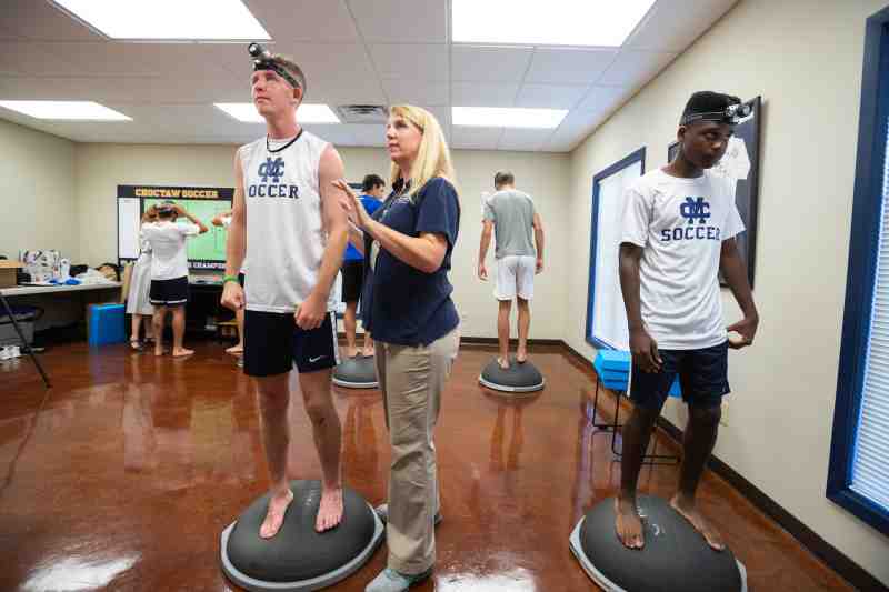 A four-week clinical research trial begins in August at Mississippi College. Dr. Kimberly Willis, a physical therapy professor at the University of Mississippi Medical Center, positions MC men's soccer players Cameron Allcorn of Pinson, Alabama and Cayman Pearson of Birmingham, Alabama on rubber stands on the Clinton campus. The rubber stands impact their balance to prepare them for a motor skills test. Photo by Joe Ellis of UMMC. 