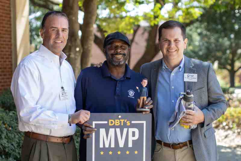 Mike Prince, left, director of food services, and Dr. Blake Thompson, right, MC president, present the October DBT's MVP Award to Derrick Martin of Campus Dining.
